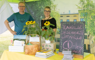 Mies ja nainen seisovat tapahtumateltan sisällä hymyillen kameralle.